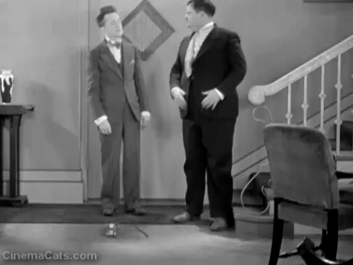 Brats - Stan Laurel trips on roller skate which rolls across room and hits tabby cat animated gif