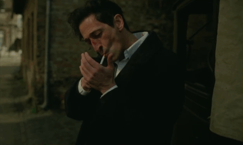 The Brutalist - László picking up tabby and white cat animated gif