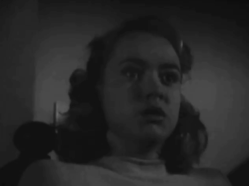 Death Walks in the Rain - La muerte camina en la lluvia - Lila Olga Zubarry turning on light to reveal close up of longhair tabby cat with small blep animated gif