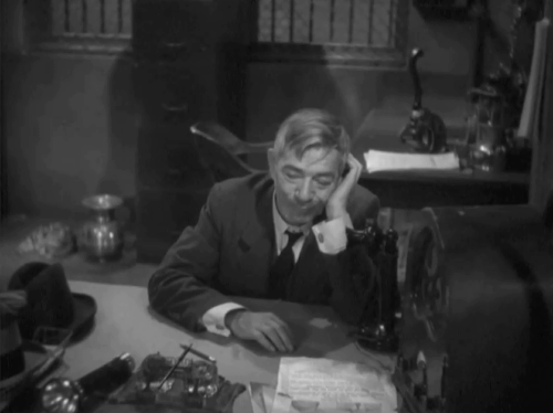 Go Chase Yourself - warden Arthur Stone looking back at tabby cat sitting next to spittoon animated gif