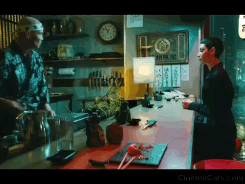John Wick 3 Parabellum - tuxedo cat lying on counter of sushi restaurant being fed by Zero Mark Dacascos and The Adjudicator Asia Kate Dillon animated gif