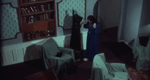 Miss Leslie's Dolls - Miss Leslie Salvador Ugarte walking past black cat Tom as he pushes himself across chair animated gif