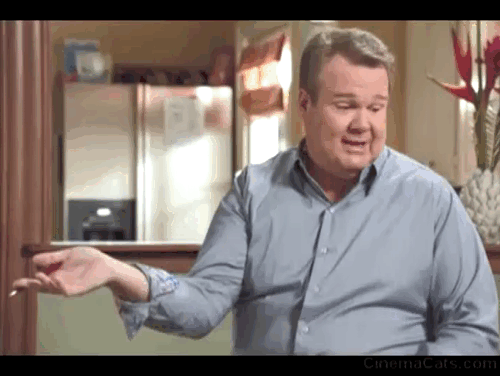 Modern Family - Larry's Wife - white cat Larry Frosty climbing onto counter behind Cameron Eric Stonestreet animated gif