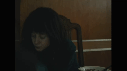 Nancy - Andrea Riseborough picking up and holding ginger and white tabby cat Paul at table animated gif