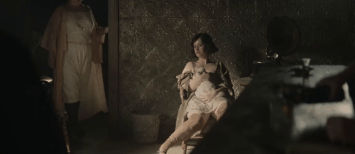 The Power of the Dog - prostitute with longhair light colored cat on her lap behind Phil Benedict Cumberbatch animated gif