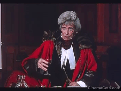 Rebecca's Daughters - Lord Sarn Peter O'Toole on magistrate bench with brown tabby cat Rover over shoulders animated gif