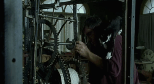 Histoire de Marie et Julien - The Story of Marie and Julien - Jerzy Radziwilowicz with tuxedo cat Nevermore Gaspard working on large clock animated gif