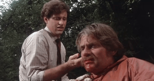 Take This Job and Shove It - Frank Robert Hays watching Ray Tim Thomerson wipe blood from mouth with the paw of a sleepy ginger and white tabby cat animated gif