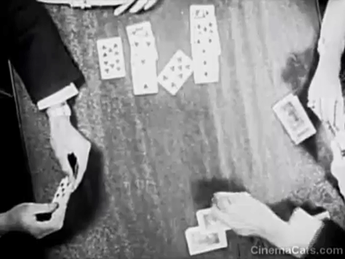 You'd Be Surprised - black cat Felix walking across card table then running past legs of couple where woman drops and breaks compact animated gif