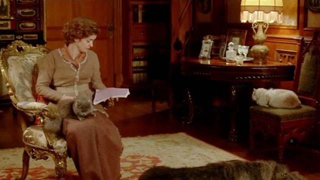 Angel - Nora Lucy Russell sitting in chair with longhair gray cat and seal point nearby