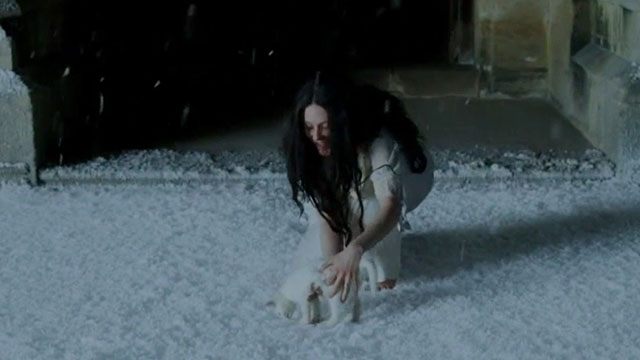 Angel - Romola Garai reaching down to pick up white kitten Silky Boy from snow