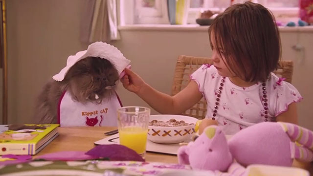 Angus, Thongs and Perfect Snogging - Smokey Persian Angus in bib and bonnet being spoon fed by Libby Eva Drew