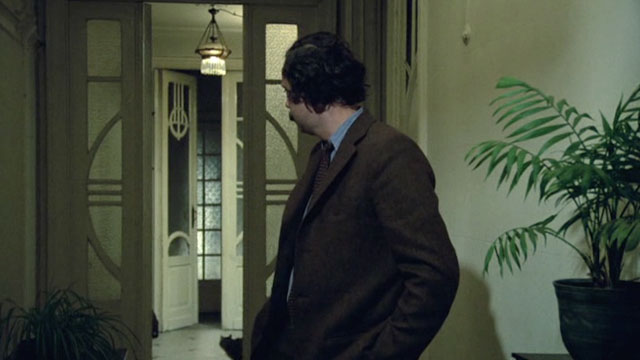 Belle - Mathieu Jean-Luc Bideau looking back at brown tabby cat Juliette by door