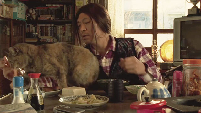 Big Man Japan - Masura Big Man Hitoshi Matsumoto at dinner table with torbie cat stealing fish