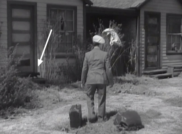 The Big Shot - Ray Eddie Quillan walking through auto camp with black cat in background