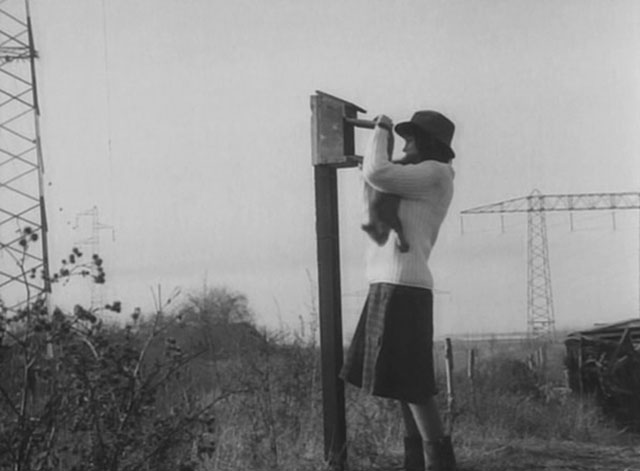 Les carabiniers - Venus Genevieve Galea with small cat climbing down from shoulder at mailbox