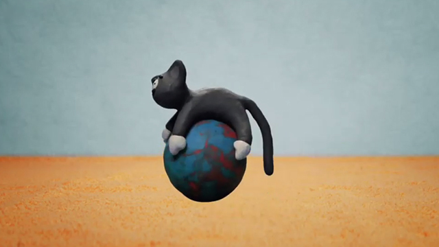 Cat in the Bag - clay black kitten with white paws bouncing on ball