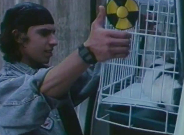 U.S. Catman Lethal Track - thug looking at tuxedo cat in cage marked radioactive