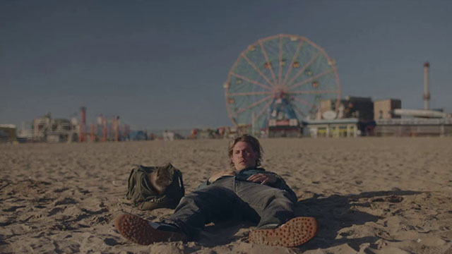 Caught Stealing - Hank Austin Butler lying on beach with longhair brown tabby cat Bud Tonic in bag