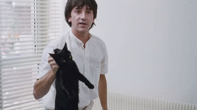 Dangerous Moves - black cat being held by scruff by Miller Jean-Hugues Anglade
