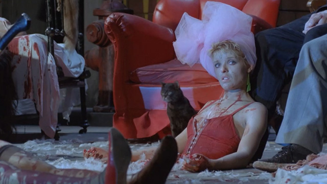 Deliria - black tabby cat Lucifer coming out from beneath chair on bloody stage covered with bodies