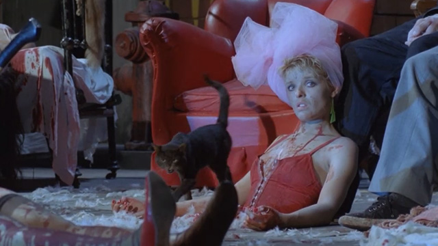 Deliria - black tabby cat Lucifer coming out from beneath chair on bloody stage covered with bodies