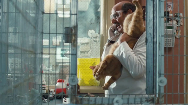 Doctor Dolittle - ginger tabby cat being taken awkwardly out of cage by Dr. Fish Jeffrey Tambor
