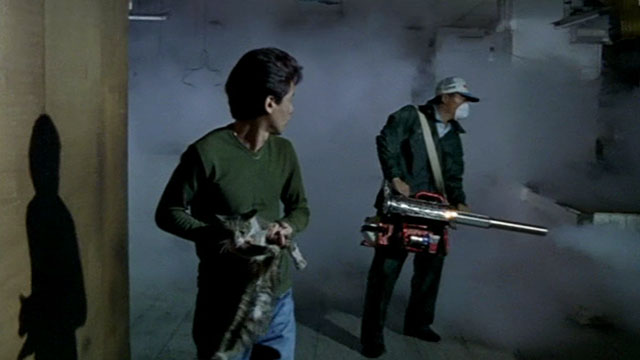 Dong - The Hole - man Kang-sheng Lee carrying tortie and white cat through marketplace being fumigated