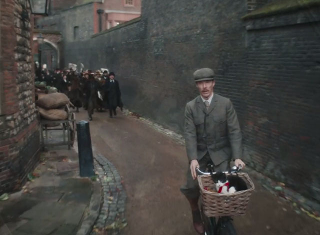 The Electrical Life of Louis Wain - Louis Benedict Cumberbatch with tuxedo cat Peter in basket of bike with crowd chasing