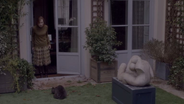 Elle - Mich&egrave;le Isabelle Huppert standing above gray cat Marty eating bird