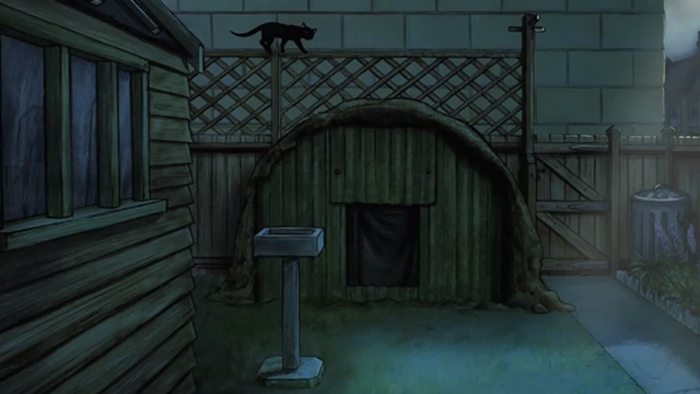 Ethel & Ernest - black cat on fence behind bomb shelter