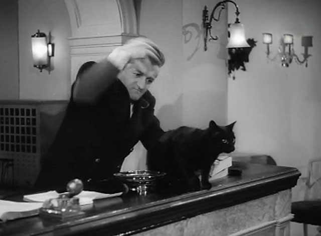 Force's Sweetheart - concierge Graham Stark placing black cat on hotel front desk