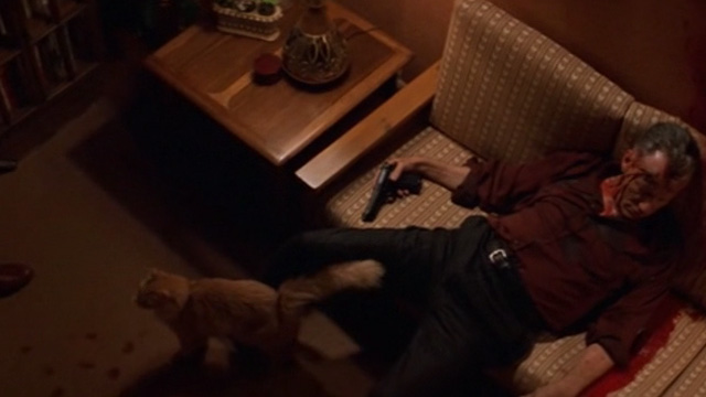 The General's Daughter - long-haired ginger cat standing in front of couch with dead and bloody Colonel Moore James Woods