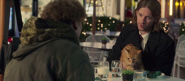 A Christmas Gift from Bob - James Bowen Luke Treadway sitting with ginger tabby street cat Bob and young man at outside table