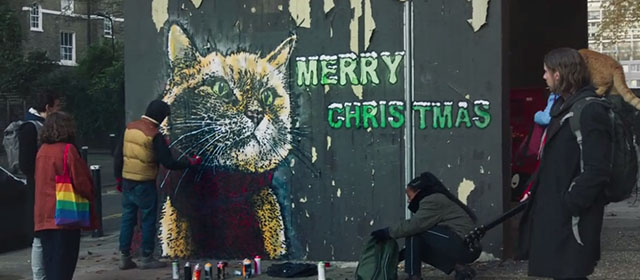 A Christmas Gift from Bob - James Bowen Luke Treadway with ginger tabby street cat Bob on shoulder looking at mural