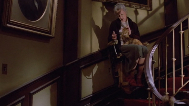 Gremlins - Mrs. Deagle Polly Holliday coming down stairs on electric chair with orange tabby cat Drachma on lap