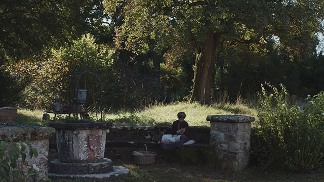 Hamnet - Judith Olivia Lynes sitting in garden with small ginger tabby cat on lap