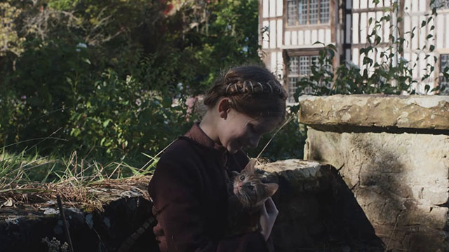 Hamnet - Judith Olivia Lynes sitting in garden with small ginger tabby cat on lap
