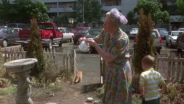 Kids in the Hall Brain candy - Mrs. Hurdicure Scott Thompson standing frozen in yard with kid and ginger tabby cat running away