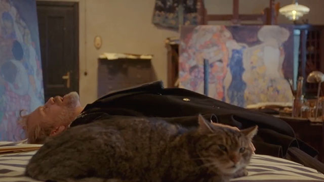 Klimt - John Malkovich lying on bed with brown tabby cat