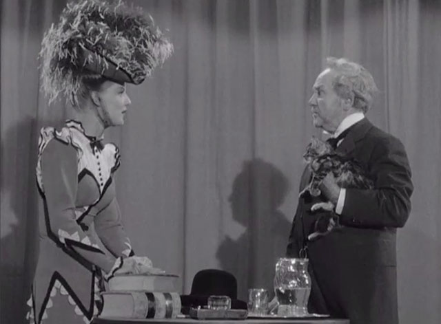Klondike Kate - Ann Savage confronting Judge Crossit George Cleveland holding small tabby cat Mr. Blackstone on stage