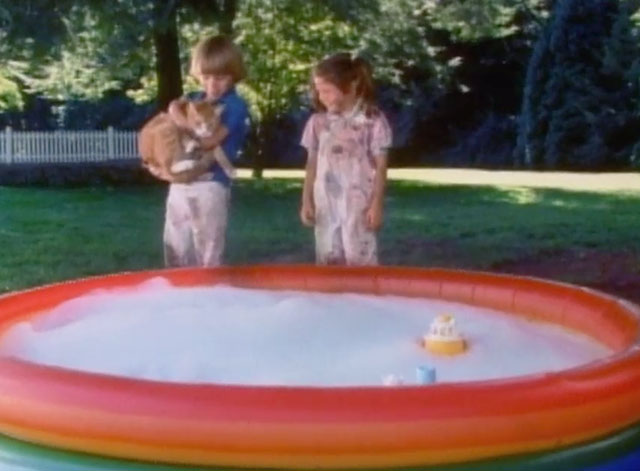 Let's Give Kitty a Bath - ginger and white tabby cat being held by Adam Bucco by kiddie pool with Amanda Jacobson