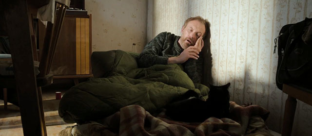 Life Eternal - Das ewige Leben - Brenner Josef Hader sleeping on floor next to tuxedo cat Erika