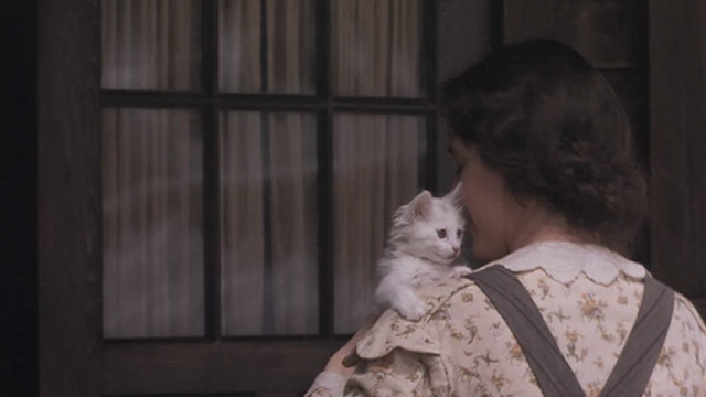 Little Women - Beth Claire Danes walking indoors with white kitten over shoulder