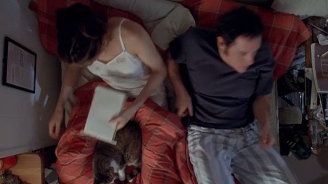 Love & Sex - Adam Jon Favreau and Kate Famke Janssen turning away from each other on bed with tabby and white cat