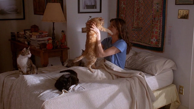 Love & Sex - Kate Famke Janssen holding up orange tabby cat with three other cats on bed