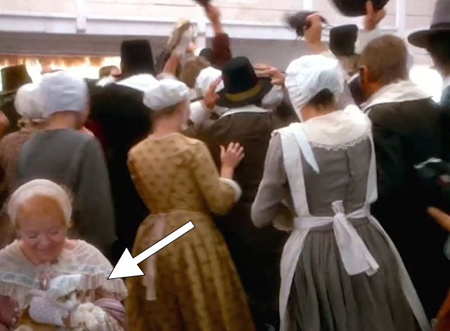 Love at Stake - Aunt Deliverence Norma MacMillan holding ginger and white tabby cat in bonnet and dress in church as everyone exits