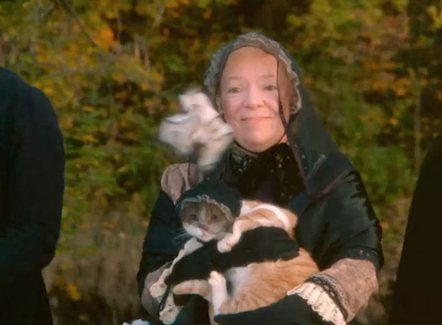 Love at Stake - Aunt Deliverence Norma MacMillan holding ginger and white tabby cat in mourning dress and veil with handerchief flying at them