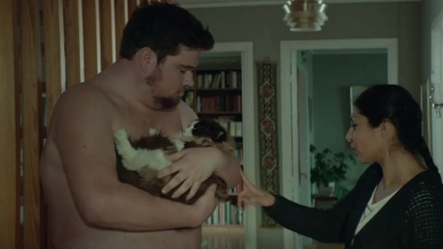 A Man Called Ove - Jimmy Klas Wiljergârd holding Ragdoll cat against bare chect with Parvaneh Bahar Pars