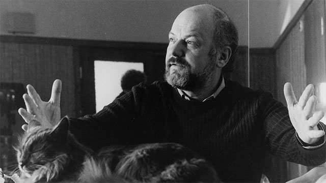 director Dusan Makavejev sitting at table with longhair cat
